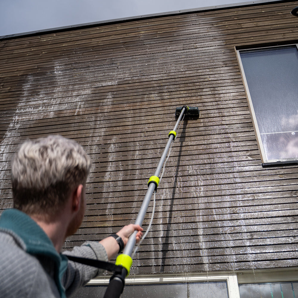 
                      
                        Person cleaning a wooden house exterior with a pressure washer.
                      
                    